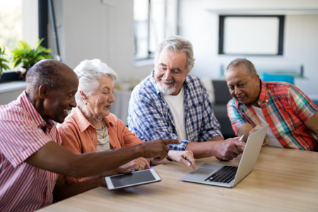 Happy mixed race senior men and woman using laptop