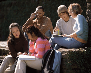 Photo of five students sitting, chatting, and studying